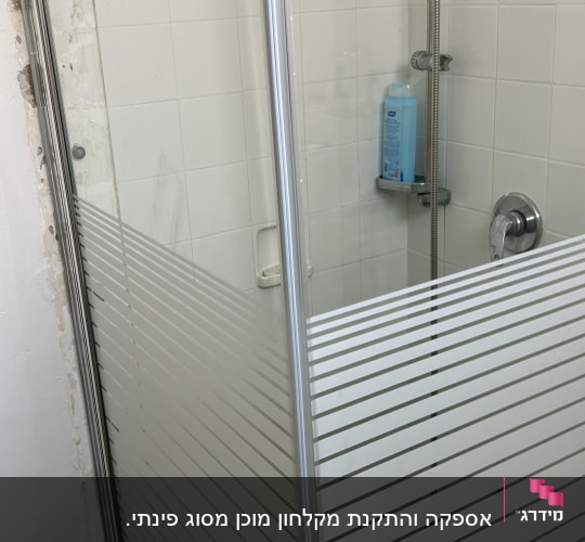 מקלחון זכוכית עם בקבוק שמפו על מדף
